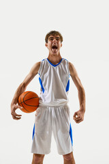 Close-up of passionate young athlete screaming with pride, holding basketball in hand against white...