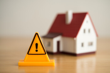 Emergency notification warning sign label with model house background. Mortgage loan for buying...
