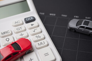 Toy cars model, black calendar and white calculator. Money financial management and calculation for buying car, car leasing, down payment, installment, auto insurance, service costs and so on concept.