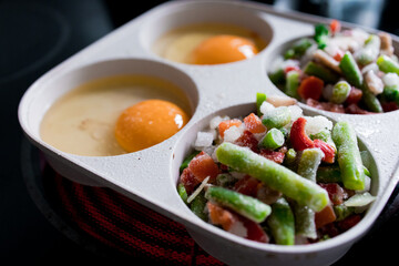 Frozen vegetables and raw eggs in tray ready for cooking