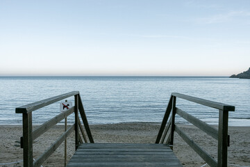 Wooden walkway leading to the beach in Costa Brava, Catalonia, Spain, captured under soft morning light, ideal for coastal retreats and tourism visuals.