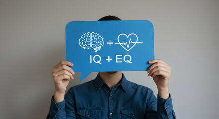 Man in Denim Shirt Holds Blue Speech Bubble with IQ Plus EQ Brain and Heart on Gray Background
