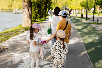 Fototapeta premium Families Walking Near a Scenic Lake on a Sunny Day
