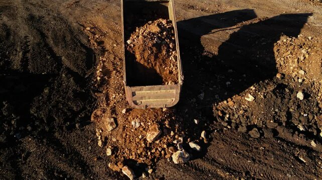 Aerial drone footage of dump truck transporting rocks and soil at construction site. Heavy machinery working with excavator and earthmoving equipment during infrastructure and industrial development p