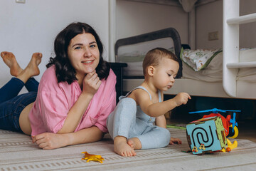 Mother and her two year old son playing in a children room, symbolizing motherhood and care
