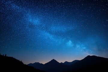 Fototapeta premium A star-filled night sky over silhouetted mountains with the Milky Way visible above the horizon.