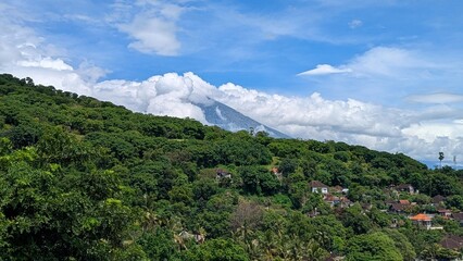Scenic aerial view of Mt Agung volcano covered in clouds in tree covered mountainous landscape of Amed in Bali, Indonesia