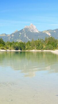 Tranquil mountain lake with emerald water and green forest edges in the Austrian Alps, peaceful natural scene at Urisee Tirol