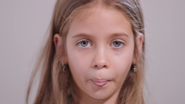 Girl sticking out her tongue and teasing while looking at the camera and then up, giving a playful expression in a close-up portrait shot