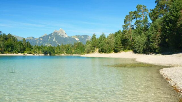 Soothing mountain scenery with turquoise lake Urisee and surrounding green hills near Reutte, peaceful nature atmosphere