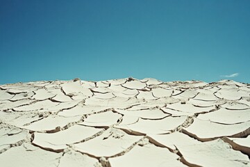 Arid expanse beneath serene skies cracked mud landscape and blue horizon minimal desert terrain