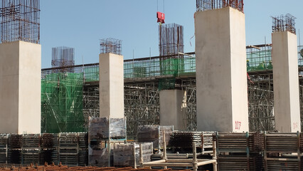 construction site with tower crane and reinforced concrete columns on-going construction