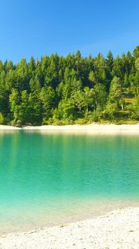 Serene view over alpine lake Urisee with turquoise water and scenic mountain forest edge in Tirol, peaceful natural vibe