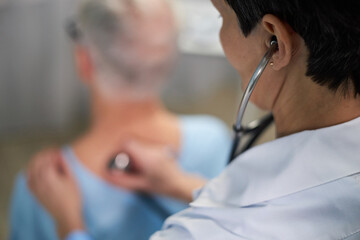 Healthcare professional using stethoscope for examining patient's heartbeat during check-up,...