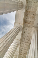 View from below of marble white columns against the sky.