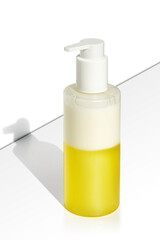cosmetic bottle with two-phase liquid: a clear, vibrant yellow oil at the bottom and a lighter cream or lotion at the top.