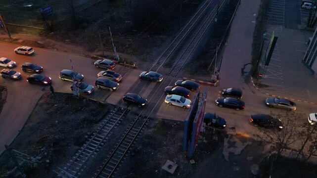 High angle shot of road cars passing over a level crossing in the night. Vehicles slowly and carefully navigating a railway railroad crossing causing congestion. Ecology concept. Establishing shot.
