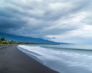 Obraz premium Dramatic storm clouds and long exposure wave motion over black sand beach showing a powerful natural landscape against a gloomy sky with dark tones and dynamic ocean waves