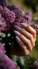 Fototapeta premium Elegant nails complement vibrant purple flowers in a serene garden setting during golden hour
