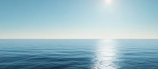 Obraz premium Calm sea under clear blue sky with sunlight glimmering on water surface.