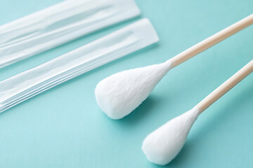 Close-up shot of cotton swabs and sealed packaging, offering a clear view of hygiene and healthcare essentials on a light blue surface.