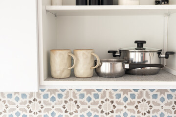Minimalist kitchen shelf with mugs and cookware