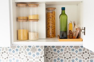 Organized kitchen pantry shelf with grains, olive oil bottle and pasta