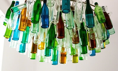 A stunning chandelier made entirely from recycled glass bottles, the lamp showcases the transformation of discarded materials into functional art and eco-friendly design.
