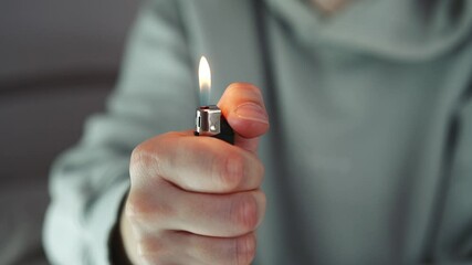 A man activates a gas lighter in his hands and demonstrates a fire