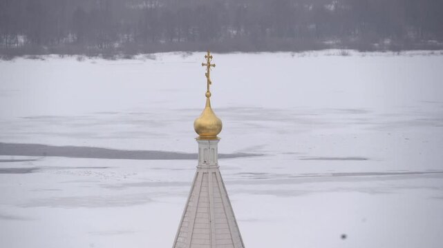 Orthodox golden cross on the dome against the background of a snowy landscape