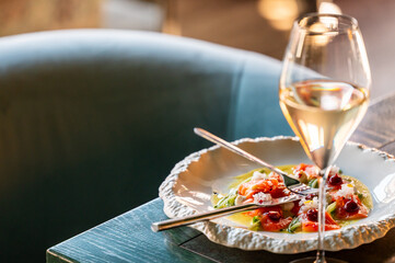 A beautifully presented gourmet dish featuring fresh seafood garnished with vibrant herbs, accompanied by a glass of white wine, set on an elegant table.