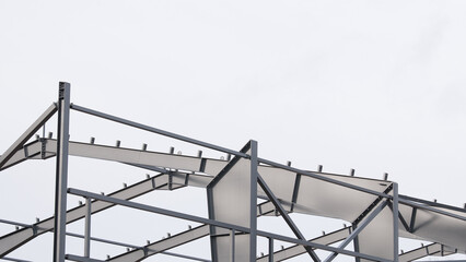 Metal construction, in the photo the structure of the building frame made of metal beams against the background of a gray sky