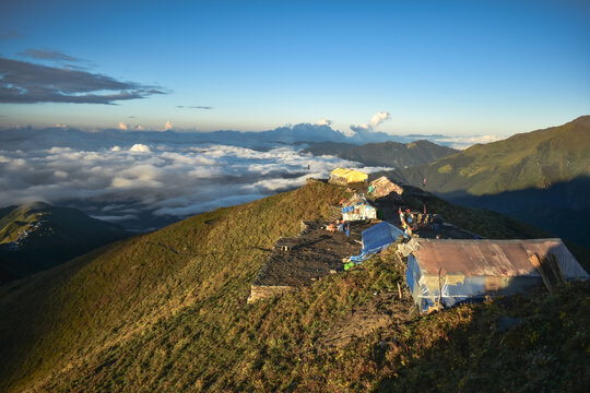 beautiful inverse cloud and green mountains with few tea shops with horizon in the warm morning light at 4200 meters above sea level at mardi himal view point, mardi himal trek , nepal.