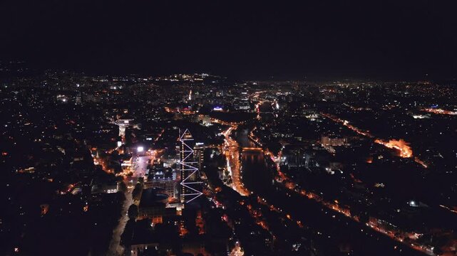 Tbilisi, Georgia - July 13 2023: Flying over Shota Rustaveli avenue in the center of city. Aerial view of The Biltmore Tbilisi Hotel at night