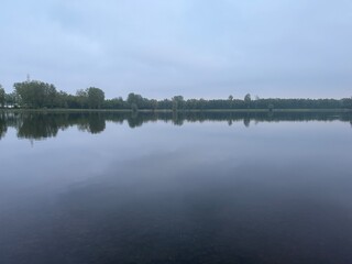 reflection of trees in the lake. Fog over the lake