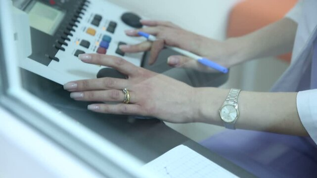 The doctor performs tinnitus measurements and monitoring of ototoxicity. Audiologist doing hearing exam the patients using audiometer in special audio room , close-up 
