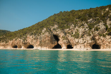 Turquoise water and white sand beach with caves in cala luna, sardinia, a popular tourist...
