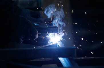 A man is welding metal with a bright blue flame
