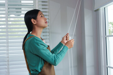 A young Asian housewife goes about her daily routine at home. She is caring, attentive, and organized, managing household tasks with dedication, warmth, and a gentle, nurturing presence.