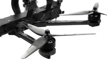 Close-up of FPV drone propeller and motor assembly on carbon fiber arm with blurred back