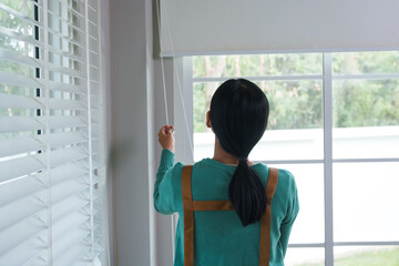A young Asian housewife goes about her daily routine at home. She is caring, attentive, and organized, managing household tasks with dedication, warmth, and a gentle, nurturing presence.