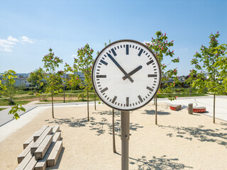 Freistehende Uhr umgeben von grünen Bäumen