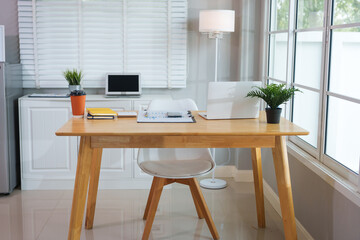 A casually dressed Asian businesswoman works from home while meeting online with a client, looking relaxed, focused and professional despite the informal setting.