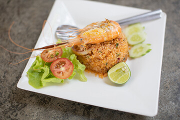 Fried rice has shrimp on top of rice in a white plate along with fresh stir-fry.