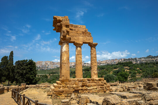 Ruins of the Temple of the Dioscuri in the Valley of the Temples in Agrigento, Sicily, Italy, a UNESCO World Heritage Site, with the city of Agrigento in the background