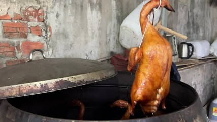 This slow motion video shows the hands of a cook hanging roasted duck in a Chinese restaurant display case.
