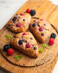 Triangular English scones with blackberries, raspberries and chocolate chips.