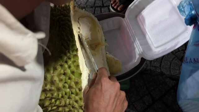 Durian packaging preparation fruit and vegetable shop keeper preparing and packaging a customer's purchase of a durian fruit.