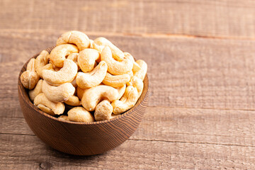 Organic roasted cashew nuts in a wooden bowl. Top view. 