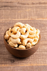 Organic roasted cashew nuts in a wooden bowl. Top view. 